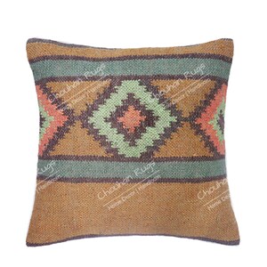 May include: A square throw pillow featuring a woven texture with a geometric pattern in shades of brown, sage green, and coral. The design includes horizontal bands and a central diamond motif. The text "Chouhan Rugs Home Decor Handloom" is visible.