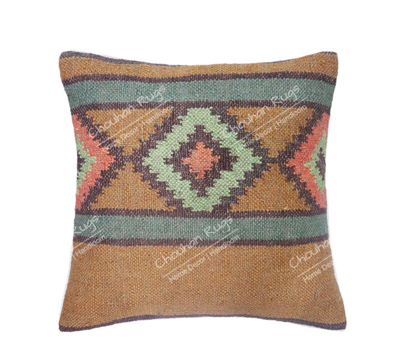 May include: A square throw pillow featuring a woven texture with a geometric pattern in shades of brown, sage green, and coral. The design includes horizontal bands and a central diamond motif. The text "Chouhan Rugs Home Decor Handloom" is visible.