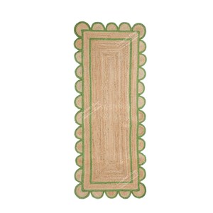 May include: A natural fiber rug with a green scalloped border. The rug is rectangular and has a woven texture.