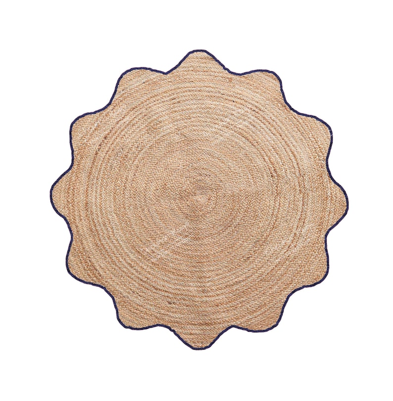 May include: A round, natural jute rug with a scalloped edge. The rug has a light brown color with a dark blue border. The jute material is woven in concentric circles, creating a textured surface. This rug is suitable for indoor use.