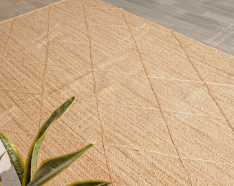 May include: A rectangular area rug made of natural tan woven fibers featuring a raised diamond pattern across the surface. The rug has a textured appearance with visible braided lines forming the geometric shapes throughout the entire piece.
