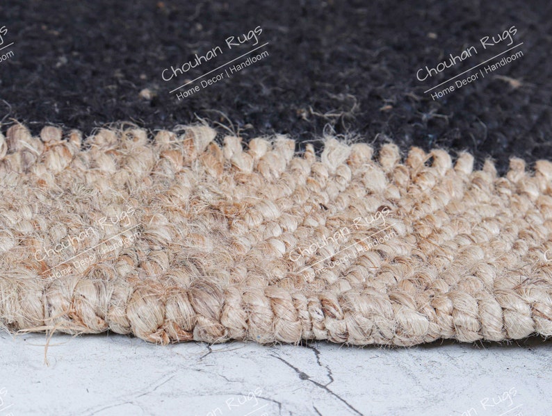 May include: Close-up of a jute rug with a black and natural color combination. The rug is handwoven and has a textured surface. The text "Chouhan Rugs Home Decor | Handloom" is visible in the image.