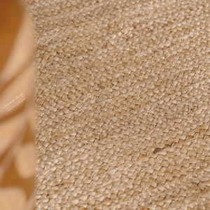 May include: Close-up of a natural fiber rug with a woven texture. The rug is a light brown color and has a slightly rough surface.