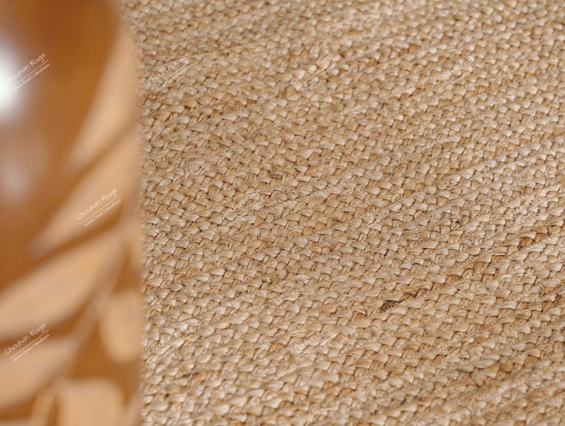 May include: Close-up of a natural fiber rug with a woven texture. The rug is a light brown color and has a slightly rough surface.
