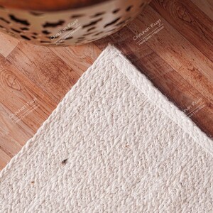 "Showcasing exceptional texture, this natural fiber rug is hand-woven using thick jute braids, resulting in a plush, tactile surface. The pale cream color reflects light beautifully, offering a bright, airy feel, making it an ideal choice for bedrooms or cozy reading nooks where comfort is key."