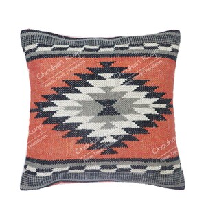 May include: A square throw pillow featuring a central geometric diamond pattern in shades of black, gray, and white against a textured burnt orange background. The top and bottom borders display a black and white checkered motif. Text reads Chouhan Rugs Home Decor Handloom.