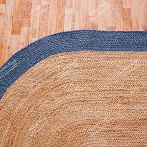 K&ouml;nnte beinhalten: Ein runder Jute-Teppich mit einem blauen Rand. Der Teppich ist aus Naturfasern gefertigt und hat einen rustikalen, erdigen Look.