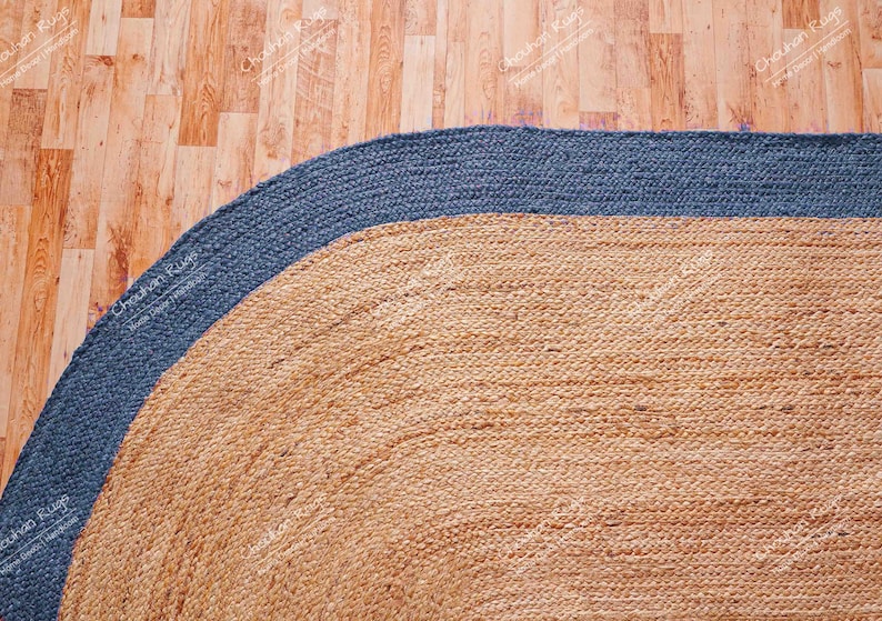 K&ouml;nnte beinhalten: Ein runder Jute-Teppich mit einem blauen Rand. Der Teppich ist aus Naturfasern gefertigt und hat einen rustikalen, erdigen Look.