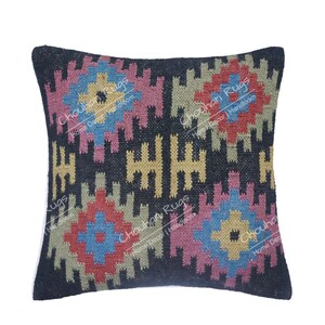 May include: A square throw pillow featuring a black background with a repeating geometric pattern in shades of blue, yellow, pink, red, and beige. The text "Chouhan Rugs Home Decor | Handloom" is overlaid multiple times across the surface of the pillow.