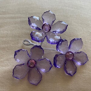 May include: Three purple crystal flower hair clips with clear rhinestones in the centre of each flower.