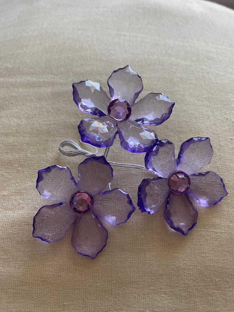 May include: Three purple crystal flower hair clips with clear rhinestones in the centre of each flower.