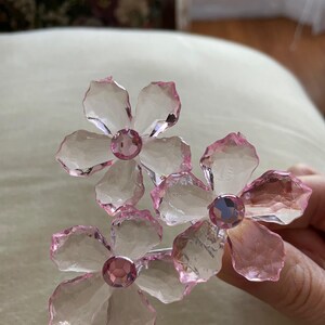May include: Three pink crystal flower hair clips with clear centres and pink rhinestones in the centre of each flower.
