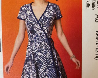 May include: A wrap dress featuring a blue and white abstract design. The dress has short sleeves, a V-neck, and a tie at the waist. The dress is a knee-length style.