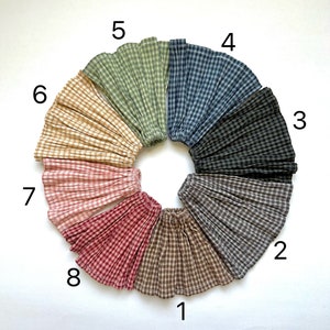 Può includere: Otto diversi campioni di tessuto gingham disposti in cerchio e numerati da 1 a 8. I campioni sono di vari colori, tra cui marrone, beige, rosso, rosa, nero, blu e verde.