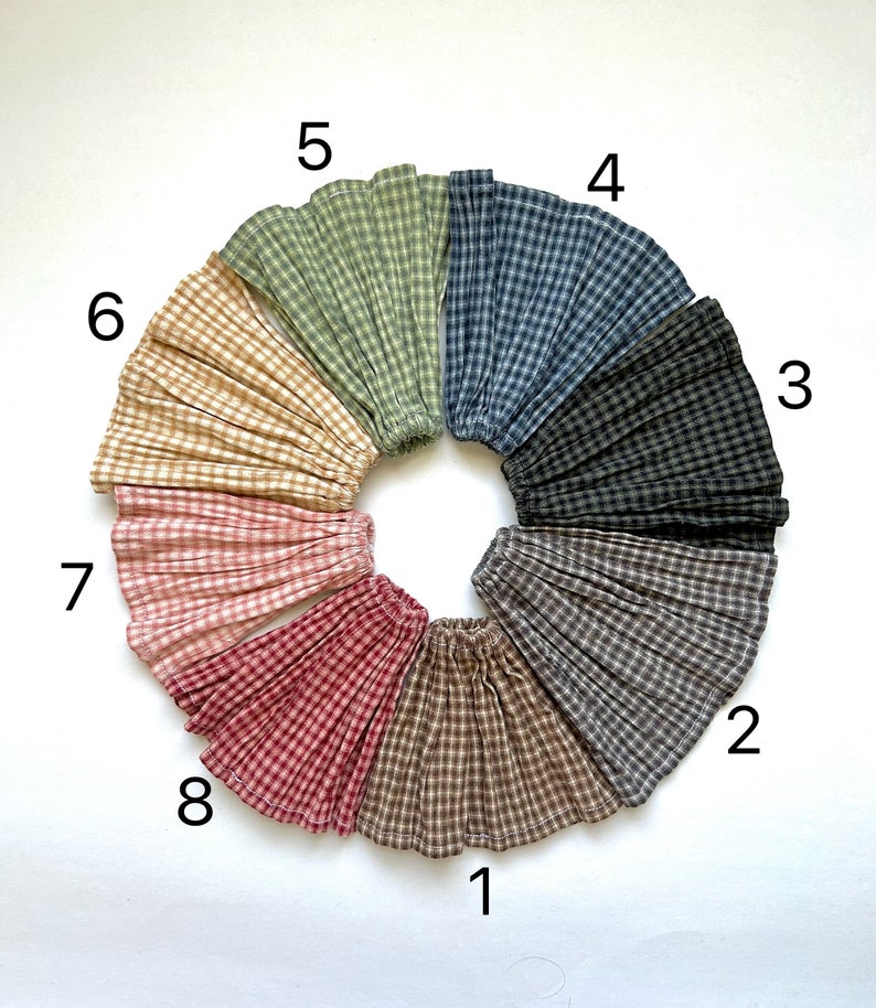 May include: Eight different gingham fabric swatches arranged in a circle, numbered 1 to 8. The swatches are in various colours, including brown, beige, red, pink, black, blue, and green.