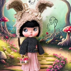 May include: A doll wearing a brown bunny hat with white lace trim, a black sweater, and a pink and white gingham skirt. The doll is holding a small basket with mushrooms. The doll is standing on a path in a woodland setting.
