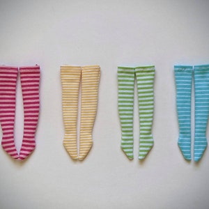 Peut inclure: Quatre paires de chaussettes rayées jusqu'aux genoux en rose, jaune, vert et bleu.