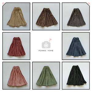 May include: Nine plaid skirts in various colours, including brown, red, blue, green, and black. The skirts are all pleated and have a simple design.
