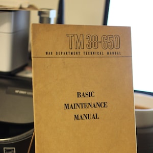May include: A brown, paper-covered manual titled "TM 38-650 War Department Technical Manual Basic Maintenance Manual" with the date "February 1947" printed on the bottom.
