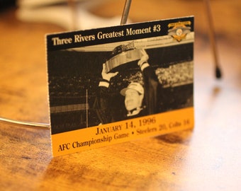 May include: A black and white photo of a football player holding up a trophy. The photo is on a card with the text "Three Rivers Greatest Moment #3" and "JANUARY 14, 1996 AFC Championship Game Steelers 20, Colts 16".