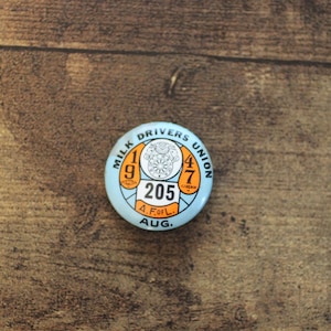 Puede incluir: Un botón circular azul y naranja con el texto "Milk Drivers Union 1947 205 A.F.of.L. AUG."