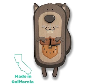 May include: A wooden squirrel-shaped clock with a brown body, a brown acorn with a clock face, and black hands. The clock face has the words "Black Forest" printed on it. The squirrel is holding the acorn in its paws. The clock is made in California with global parts.