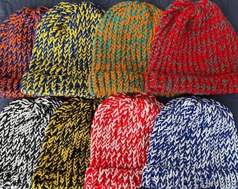 May include: A collection of handmade knit beanies in various colors, including orange, yellow, green, red, black, and blue. Each hat features a ribbed brim and a textured knit pattern, perfect for cold weather.