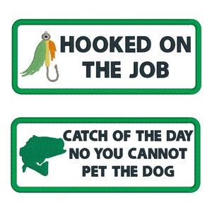 Könnte beinhalten: Zwei rechteckige grüne und weiße Patches mit gesticktem Text und Bildern. Der obere Patch hat einen grünen, orangefarbenen und weißen Angelköder mit dem Text "HOOKED ON THE JOB". Der untere Patch hat eine grüne Fischsilhouette mit dem Text "CATCH OF THE DAY NO YOU CANNOT PET THE DOG".
