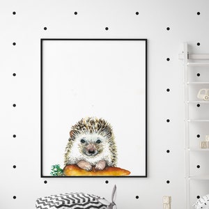 May include: A watercolor painting of a hedgehog holding a carrot. The hedgehog is brown and white with a pink nose. The painting is framed in a black frame and is hanging on a white wall with black polka dots.