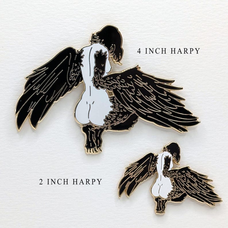 Two different sized enamel pins showing a large 4 inch of black haired Harpy mythical creature with a 2" inch black haired Harpy mythical creature. Both harpies are gold enamel pins with black wings and an exposed buttocks.