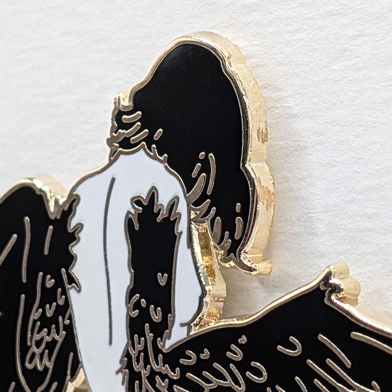 Close up showing detail of black haired Harpy mythical creature with black and gold enamel pin detailed wings.