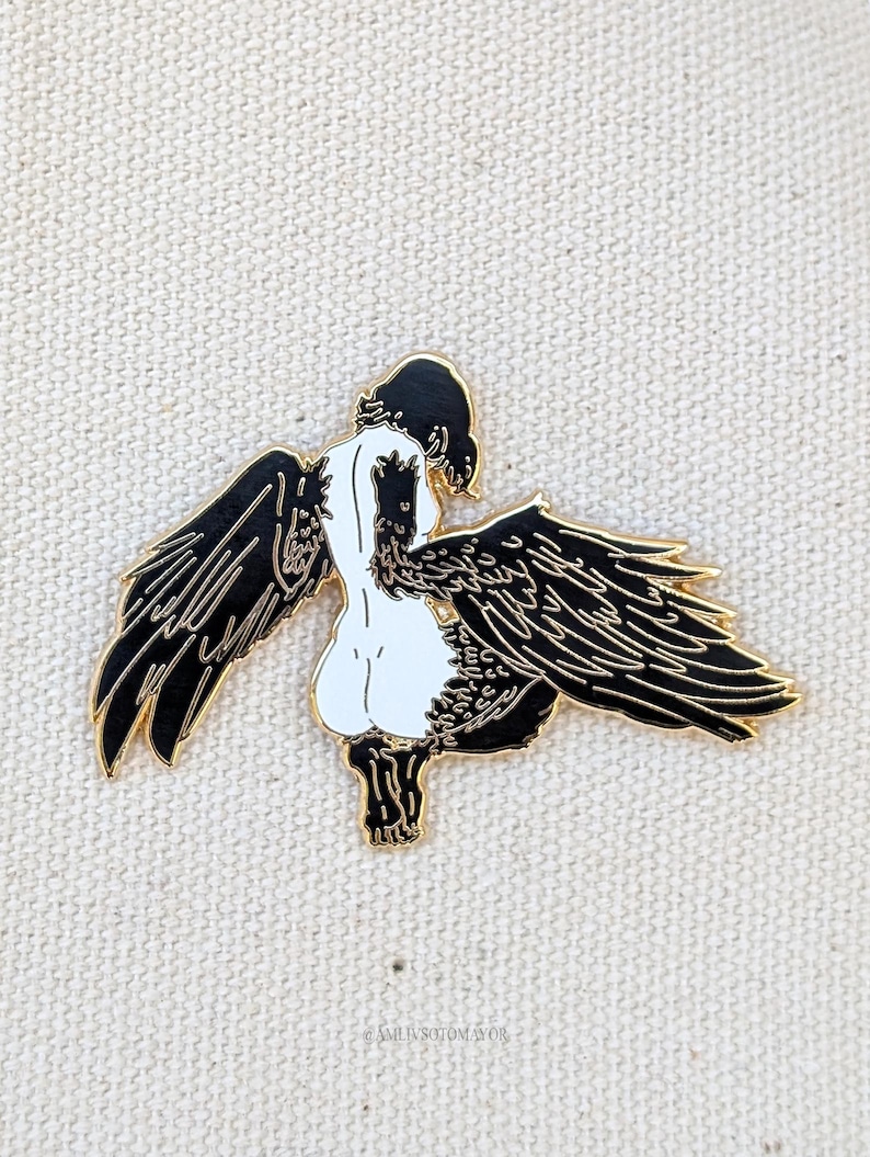 Harpy mythical creature enamel pin detailed wings gold enamel displayed against textured canvas