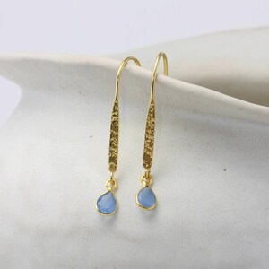 May include: A pair of gold dangle earrings with light blue teardrop-shaped stones.