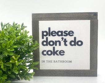 May include: A wooden sign with the text "please don't do coke in the bathroom" in black lettering on a white background.