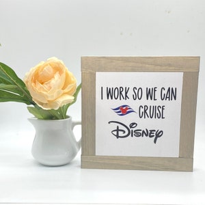 May include: A wooden sign with the text "I work so we can cruise Disney" with a Disney cruise ship logo and Mickey Mouse ears.