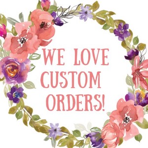 May include: A watercolor floral wreath with pink and purple flowers and green leaves. The wreath surrounds the text "WE LOVE CUSTOM ORDERS!" in pink.