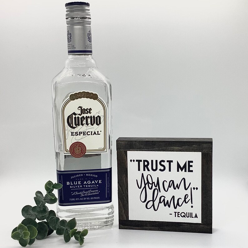 Puede incluir: Un letrero de madera con texto negro que dice "TRUST ME you can dance! - TEQUILA" est&aacute; al lado de una botella de tequila Jose Cuervo Especial Blue Agave Silver.