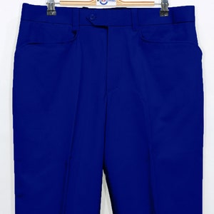 May include: A pair of blue pants hanging on a wooden hanger. The pants have a button closure and two front pockets.