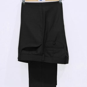 May include: Black dress pants hanging on a wooden hanger. The pants have a single button on the back pocket.