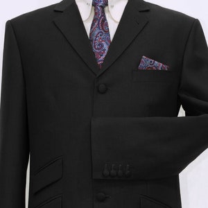 May include: A black suit jacket with a three-button closure, a paisley patterned tie, and a matching pocket square. The jacket has a notched lapel and flap pockets.