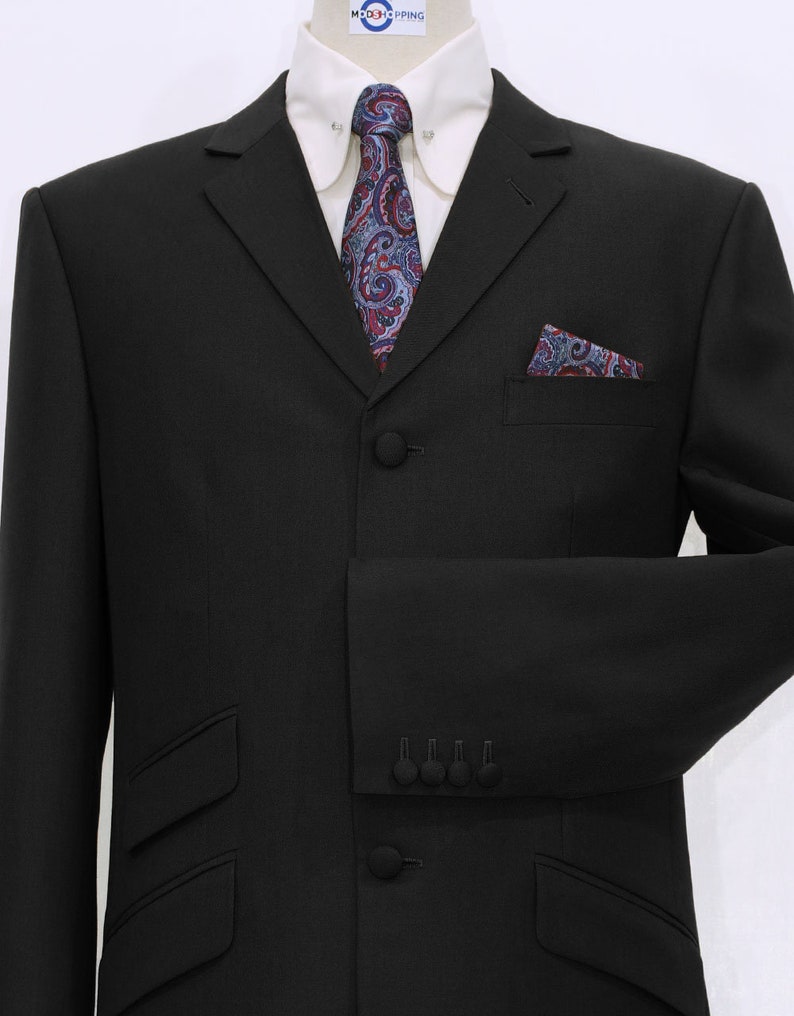 May include: A black suit jacket with a three-button closure, a paisley patterned tie, and a matching pocket square. The jacket has a notched lapel and flap pockets.