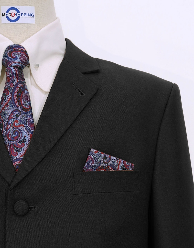 May include: A black suit jacket with a paisley patterned pocket square and tie. The jacket has a single button closure and a notch lapel.