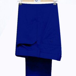 May include: A pair of royal blue dress pants hanging on a wooden hanger. The pants have a single back pocket with a button closure.