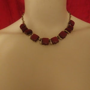 Könnte beinhalten: Eine goldene Kettenkette mit quadratischen Perlen in Marone.