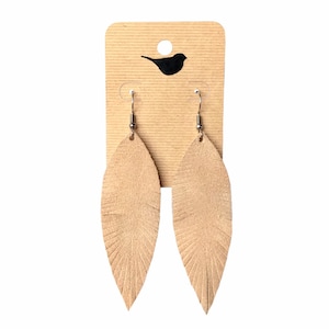 May include: A pair of tan leather feather earrings with silver hooks. The earrings are displayed on a brown card with a small bird silhouette.