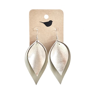 May include: A pair of silver and beige leather earrings with a teardrop shape.