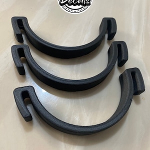 May include: Three black plastic clamps, each with a curved shape and a hook on one end. The clamps are stacked on top of each other.
