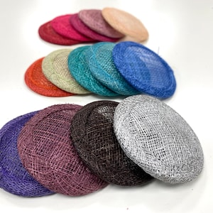 May include: A collection of 12 round, flat, woven hats in various colours, including purple, blue, teal, green, beige, red, pink, and grey.