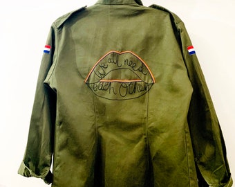 Chaqueta tipo camisa militar vintage bordada a mano con la frase "Lee mis labios: todos nos necesitamos".