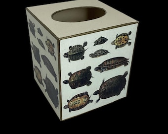 May include: A cream-coloured square tissue box featuring illustrations of turtles. The box has a rectangular opening on top and gold trim. The turtles are depicted in various sizes and colours, creating a vintage aesthetic.